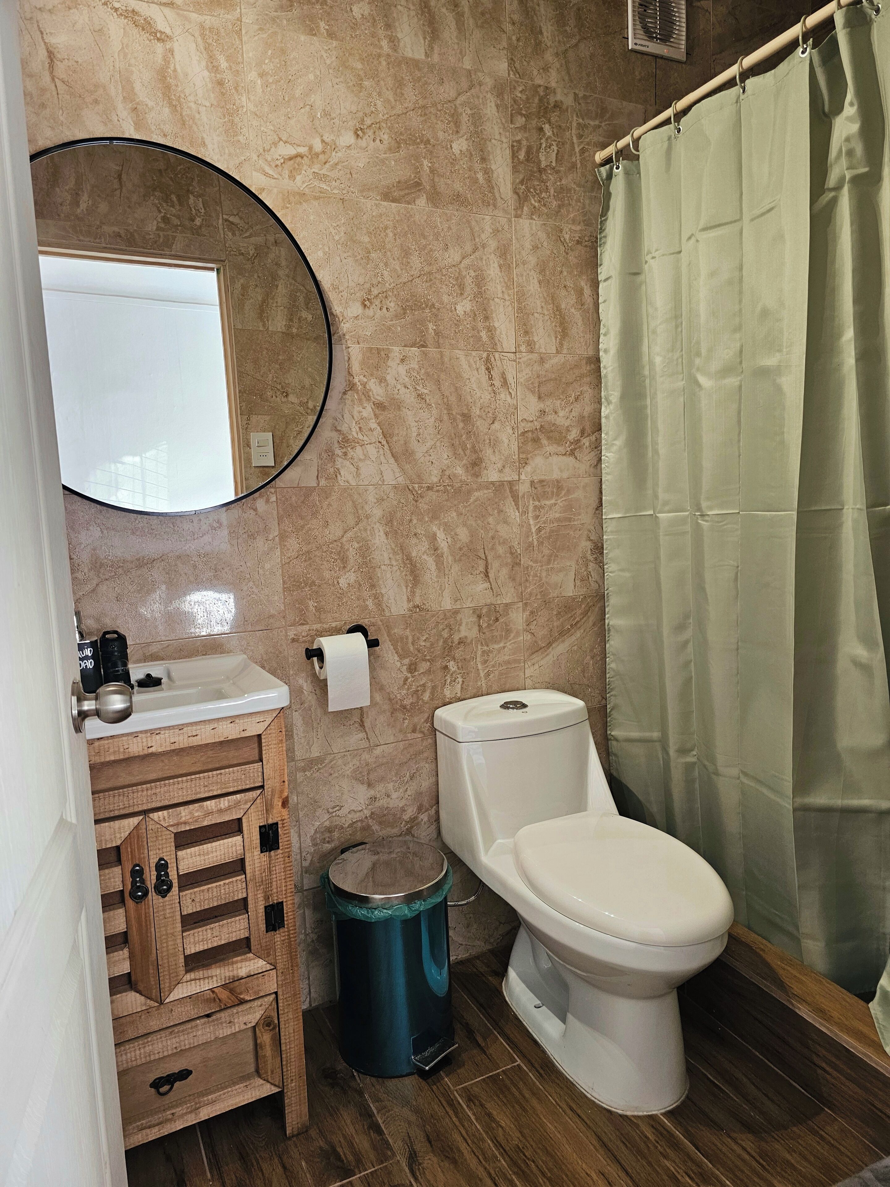 Un baño con inodoro, lavamanos, espejo y cortina de ducha.