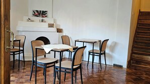 A room with a herringbone wooden floor, a fireplace, and a dining area with chairs and tables. - Forest Hostel B&B (Santiago)