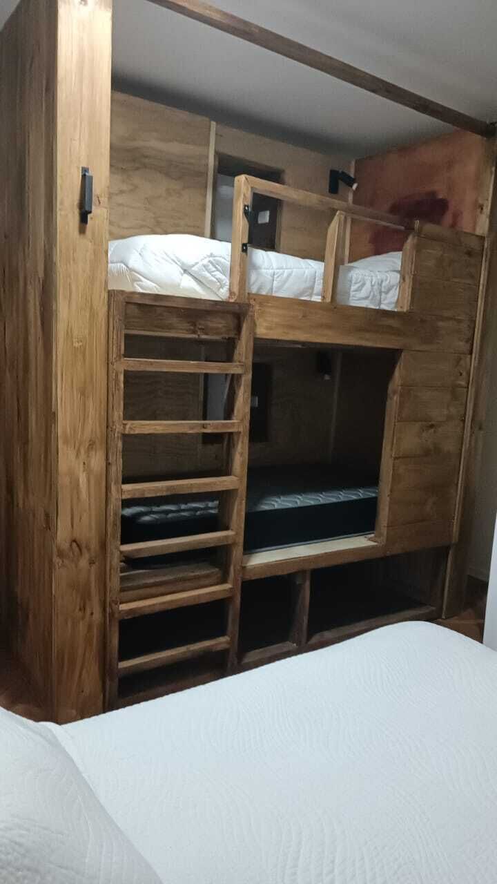Een stapelbed met een houten ladder en een onderbed.