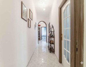 A hallway with a marble floor, framed pictures on the wall, and a wooden door with glass panels. - Holiday apartment mit Klimaanlage und Balkon (Imperia)