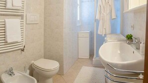 Un baño moderno con inodoro, bidé, ducha y un lavamanos grande.