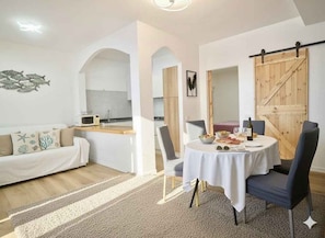 Ein modernes Wohnzimmer mit Esstisch, einer Couch und einem durch einen Bogen sichtbaren Küchenbereich.