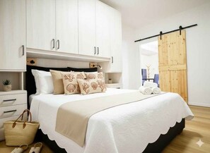 Ein Schlafzimmer mit einem Bett, weißen Schränken, einer Holztür und einer kleinen Pflanze.