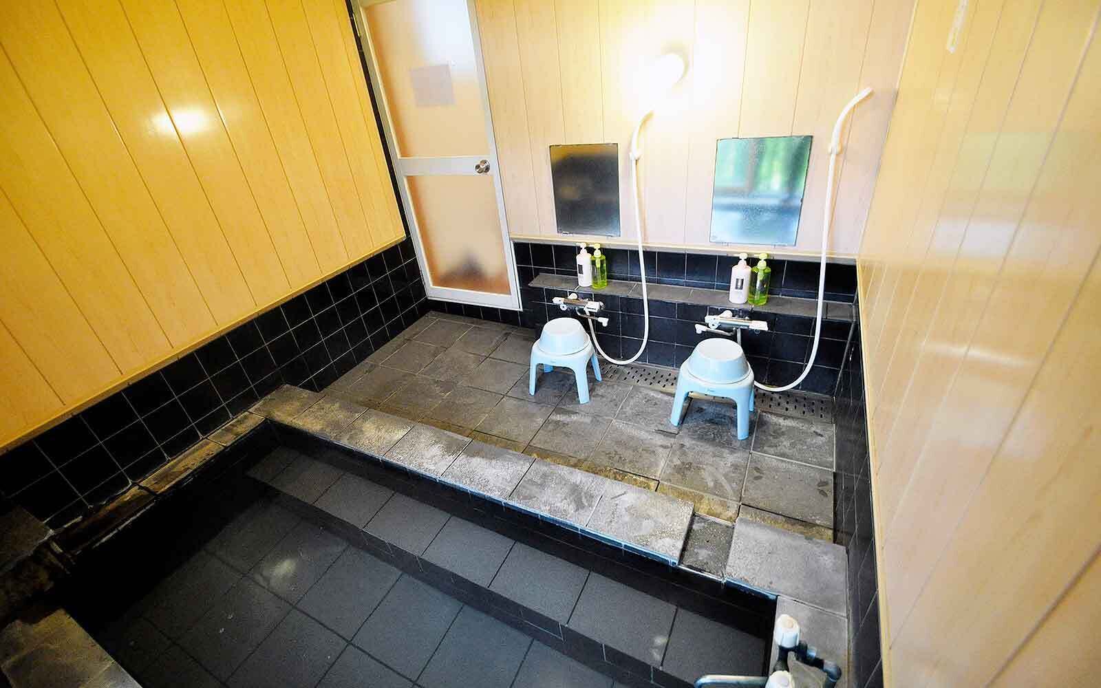 Een kleine badkamer met twee wasbakken, een spiegel en een douchehoek.