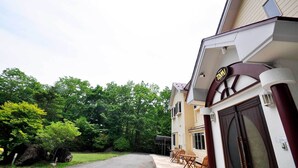 A building with a sign reading 'TAM,' a covered outdoor seating area, and a driveway leading to the entrance.