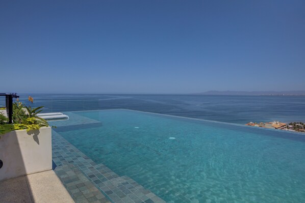 Ein klares, blaues Infinity-Pool mit Blick auf das Meer und die Ferne.