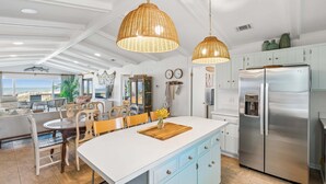 Cucina moderna con isola centrale ampia, elettrodomestici in acciaio inossidabile e lampade a sospensione in vimini.