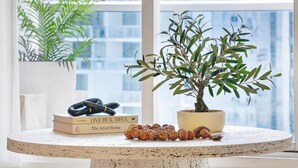 Uma mesa redonda com um vaso de planta, livros e um objeto decorativo.