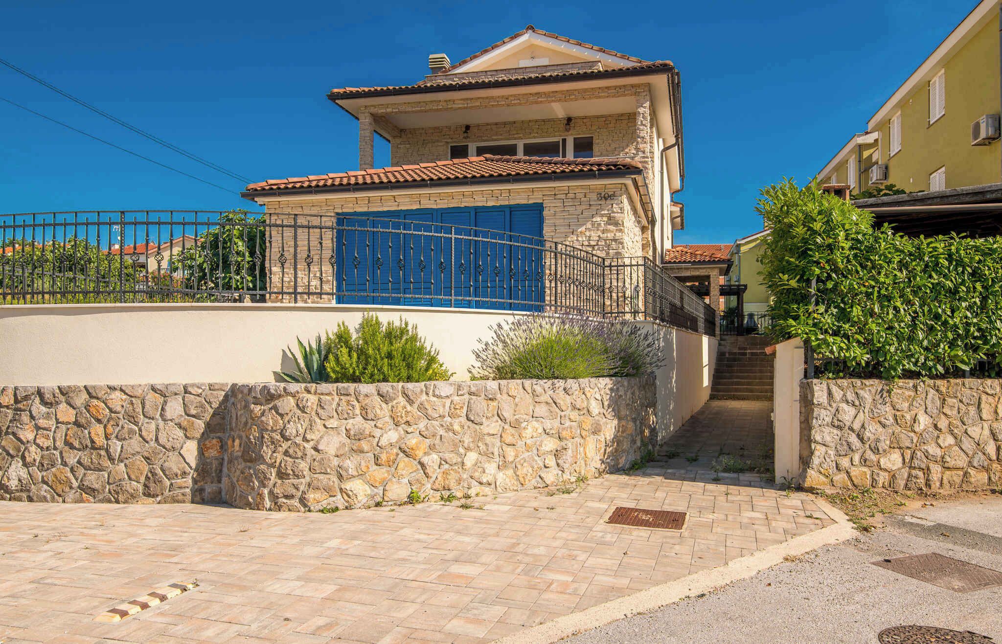 Edifici de murs de pedra amb teulada de rajola, una porta blava i un vestíbul pavimentat.