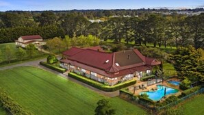 A large house with a swimming pool, surrounded by well-maintained lawns and trees. - Peninsula Farm heated spa, fireplace & fire pit (Somerville)