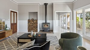 A spacious living room with a fireplace, a sofa, a coffee table, and a view of the outdoors. - Peninsula Farm heated spa, fireplace & fire pit (Somerville)