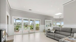 A spacious living room with a grey sofa, a fireplace, and large sliding glass doors leading to a balcony. - Peninsula Farm heated spa, fireplace & fire pit (Somerville)