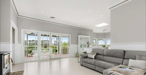 A spacious living room with a grey sofa, a fireplace, and large sliding glass doors leading to a balcony.