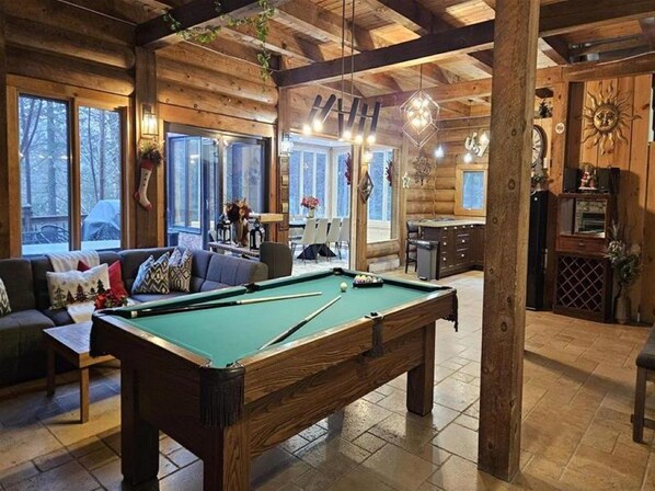 Ein gemütliches Blockhaus-Interieur mit Billardtisch, einer Couch und einem Essbereich.