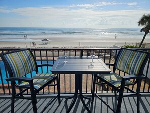 Eine Terrasse direkt am Strand mit Tisch und Stühlen, mit Blick auf das Meer.