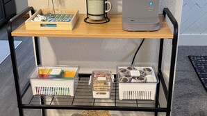 A kitchen cart with a coffee maker, a mug holder, and storage containers.