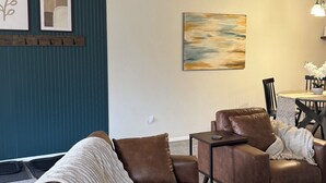 A modern living room with a sectional sofa, a coffee table, and a dining area with a table and chairs.