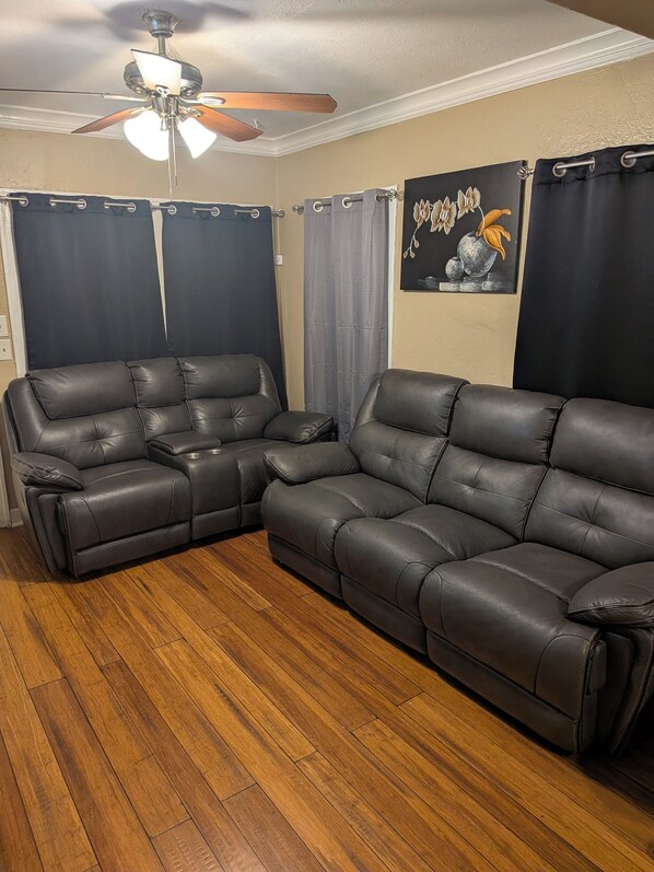 A living room with a sectional sofa, a ceiling fan, and a painting on the wall. - 2-bedroom Remodeled  delightful Bungalo style house Kansas City with cental AC (Kansas City)