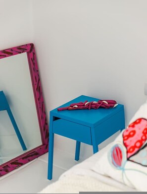 A room with a blue chair, a mirror with a pink frame, and a bed with a white and red patterned blanket. - Sunkissed Apartment 1BR Amazing Views by the Sea (Sarandë)