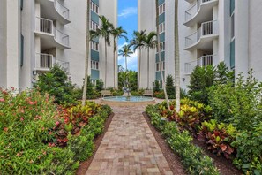 A multi-story hotel with a central courtyard, palm trees, and a water feature. - Coastal Retreat Near the Beach and 5th Ave (Naples)