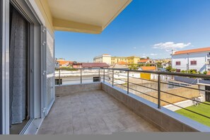 A balcony with a view of neighboring buildings and a clear sky.