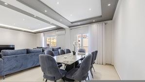 Una sala moderna con un sofá modular, una mesa de comedor con sillas y un amplio ventanal.