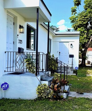 A white two-story house with a front porch, a mailbox, and a door. - Modern Miami Retreat w/ Games (Miami)