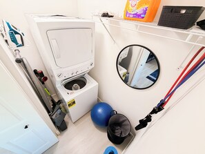 Ein kleiner Waschbereich mit Waschmaschine, einer Mini-Hantel und einem Spiegel.