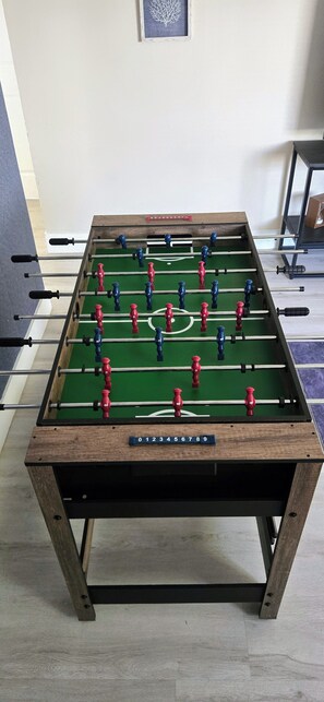 Ein Kicker mit Holzrahmen und grüner Spielfläche.