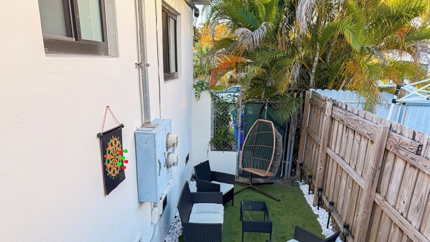 A patio with outdoor furniture, a ping pong table, and a wooden fence. - Modern Miami Retreat w/ Games (Miami)