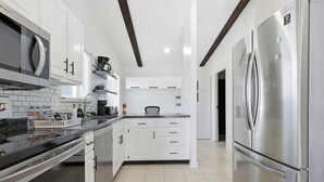 A modern kitchen with white cabinets, a stainless steel refrigerator, and a black countertop. - Gorgeous 3-bedroom house with AC in pleasant Fishers (Fishers)
