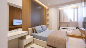 Un dormitorio moderno con cama, televisión, bañera y tocador.