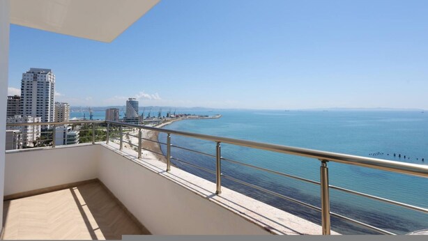 Un balcone con vista sul mare e sugli edifici.