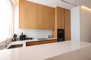 A modern kitchen with wooden cabinets, a countertop, a sink, and a built-in oven. - Grandstay Sea Penthouse 02 (Durrës)