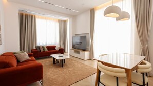 Un soggiorno moderno con divano, tavolino, televisore e zona pranzo con tavolo e sedie.