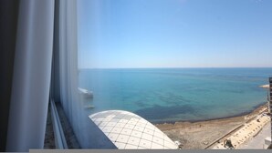 A view from a window overlooking a coastal area with a clear sky, a large white dome structure, and a construction site. - Grandstay Sea Penthouse 01 (Durrës)