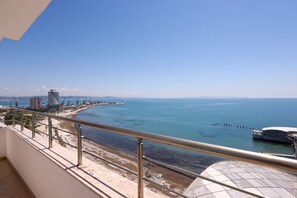 Ein Balkon mit Blick auf das Meer, einen Strand und ein modernes Gebäude.