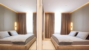 A mirrored room with two beds, a central light fixture, and vertical paneling on the walls. - Grandstay Sea Penthouse 01 (Durrës)