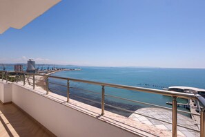 Ein Balkon mit Blick auf das Meer, ein Gebäude und ein klarer Himmel.