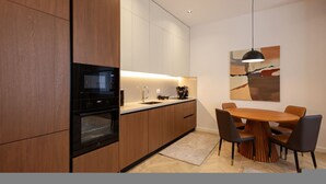 Une cuisine moderne avec des meubles en bois, un four encastré, une table à manger avec des chaises et un luminaire suspendu.