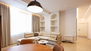 Un salon moderne avec une grande table en bois, un canapé beige et une bibliothèque intégrée.
