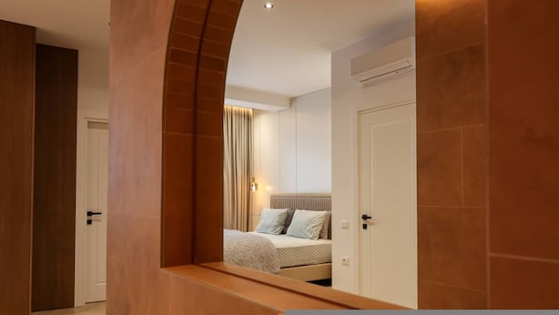 Une chambre à coucher moderne avec un lit, une table de chevet et un miroir qui reflète la pièce.
