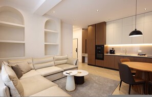 A modern living room with a sofa, a coffee table, and a dining area with a table and chairs. - Grandstay Sea Penthouse 04 (Durrës)