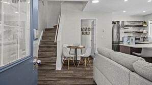 A modern kitchen with a refrigerator, microwave, and a dining area with a table and chairs. - Cozy Rockies Stay with Hot Tub and Fire Pit (Harvie Heights)