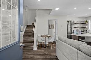 Una cocina moderna con refrigerador, microondas y un comedor con mesa y sillas.