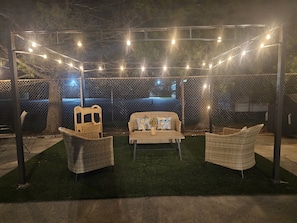 An outdoor seating area with wicker furniture, a table, and string lights.