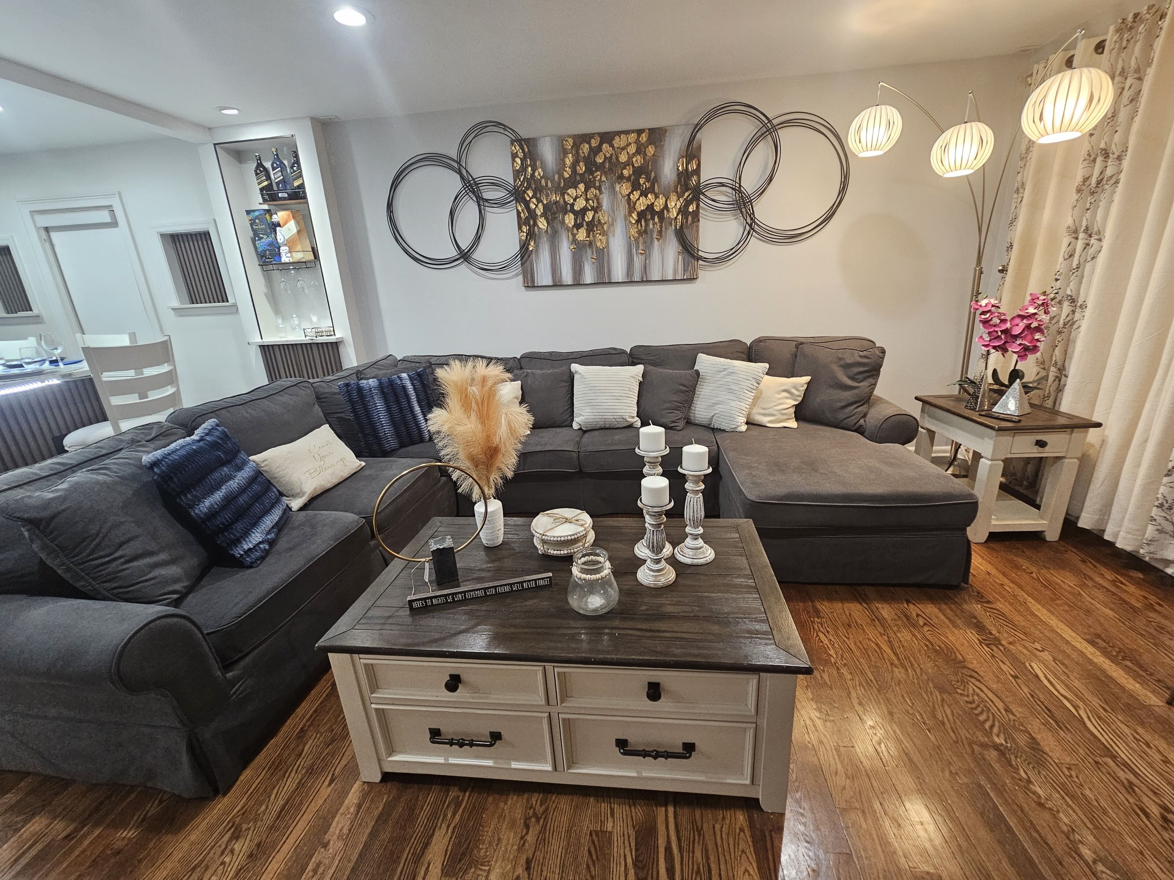 A modern living room with a sectional sofa, a coffee table, decorative wall art, and a side table with a vase.
