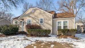 A single-story house with a front porch, a covered entryway, and a small front yard with snow. - Sleeps 6, Quiet & Safe, Easy drive to Arrowhead! (Overland Park)