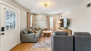 A modern living room with a sofa, armchairs, a coffee table, a TV, and a ceiling light. - Sleeps 6, Quiet & Safe, Easy drive to Arrowhead! (Overland Park)
