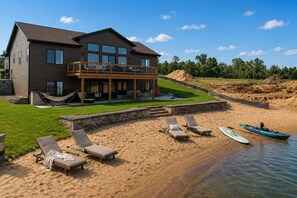 A modern house with a deck, a sandy beach, and a kayak. - Jimmy’s Beach House | Private Beach + Arcade (New Lisbon)